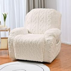 a white chair sitting on top of a hard wood floor next to a rug and window