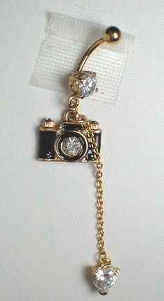 a gold camera with a chain attached to it's side hanging from a white wall