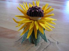 a small yellow flower sitting on top of a wooden floor