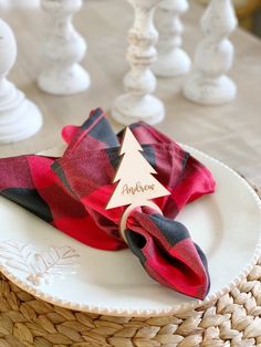 a plate with a red and black plaid napkin on it next to a christmas tree place card holder