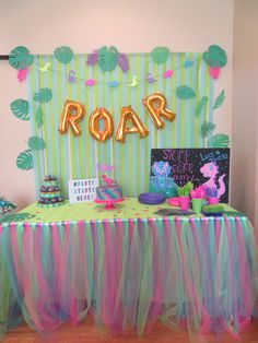 a table topped with cake and balloons in front of a sign that says roar on it