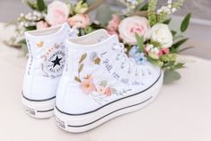 a pair of white sneakers with flowers on the bottom and one shoe has writing on it