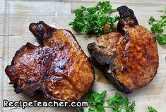 two pieces of meat sitting on top of a wooden cutting board next to parsley