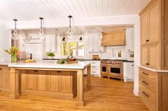 a large kitchen with wooden floors and white walls, has an island in the middle