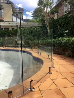 an empty swimming pool with glass fencing around it