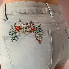 a woman's jeans with embroidered flowers and mushrooms on the back pocket is shown