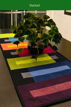 a potted plant sitting on top of a multicolored table runner next to a window