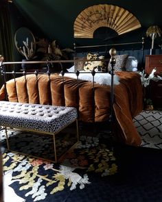 a bed with a leopard print foot stool in front of it and a fan on the wall behind it