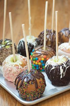 several chocolate covered donuts with sprinkles and candy on them sitting on a tray