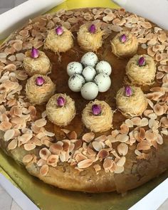 a cake in a box with eggs and almonds on the top, surrounded by shells