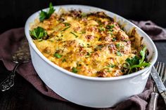 a casserole dish with meat, cheese and herbs in it on a table