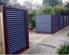 a row of closed metal doors on the side of a sidewalk in front of a house