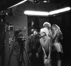 a group of people standing in front of a camera on a tripod with one person dressed as marilyn monroe