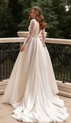 a woman in a white wedding dress standing on a balcony with her hands on her hips