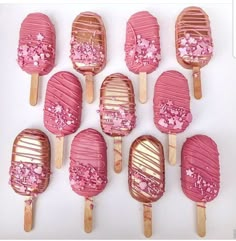 there are many pink and gold lollipops on sticks