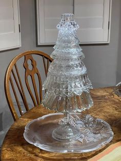 a glass christmas tree sitting on top of a wooden table