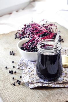 a jar of blueberry jam next to a bowl of blackberries on a table