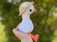 a crocheted duck with a hat on it's head sitting in someones hand