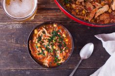 two bowls filled with soup next to a glass of beer on top of a wooden table