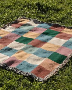 a multicolored blanket laying on the grass