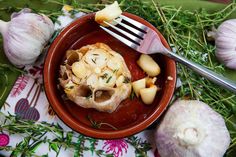 a bowl filled with food next to some garlic and other vegetables on top of a table