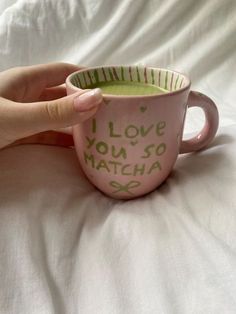 a hand holding a coffee mug with the words i love you so matcha written on it