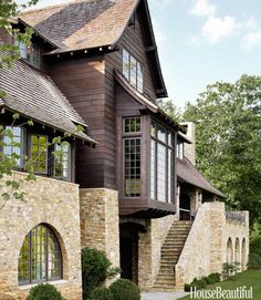 a large house with stone and wood sidings on the front, stairs leading up to it