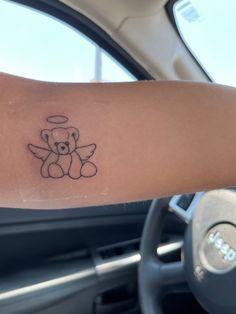 a small teddy bear tattoo on the arm