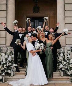 a group of people that are standing in front of a building with flowers on the steps