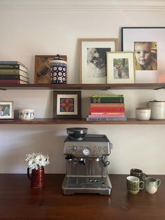 a coffee maker sitting on top of a wooden table next to a shelf filled with books