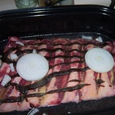 the meat is being cooked in the oven with onion slices and onions on it's sides