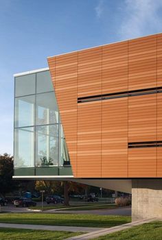 the side of a building that is made out of wood and glass, with grass in front