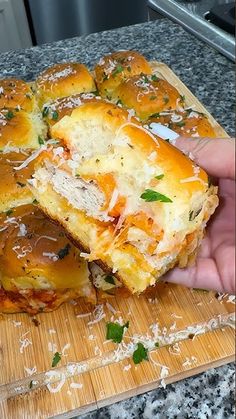 someone is holding up some food on a cutting board with cheese and meat in it