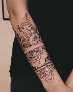 a woman's arm with flowers and leaves tattooed on the side of her arm