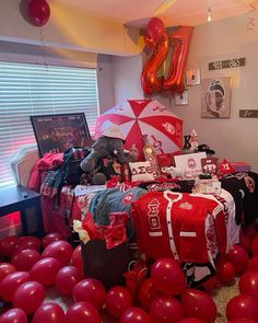 a room filled with lots of red balloons and bags on the floor next to a window