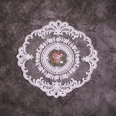 a white doily sitting on top of a gray floor next to a pink rose