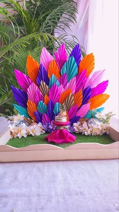 an arrangement of colorful paper fan flowers in a wooden box with pink ribbon on top