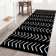 a black rug with white arrows on it in the middle of a room next to a table