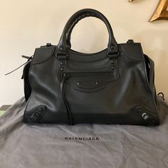 Balenciaga "Neo Classic City" Top Handle Bag In Supple Calf Leather Features Signature Studs And Buckle Hardware Rolled Top Handles Detachable, Adjustable Shoulder Strap Recessed Zip Top Closure Exterior, Front Zip Pocket Lining: Leather Feet Protect Bottom Of Bag Approx. 9.6"H X 15.3"W X 6.3"D Spot Clean Made In Italy Purchased At Bergdorf Goodman 2023 Gently Used Dust Bag Included Minor Markings On Outside From Use. Leather Is Very Soft Pet And Smoke Free Home Balenciaga Classic City Bag, Balenciaga Neo Classic, Balenciaga Classic City, Bags Balenciaga, Neo Classic, Balenciaga Bag, City Bag, Handle Bag, Bergdorf Goodman