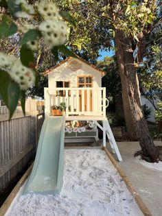 a small white house with a slide in the yard