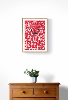 a wooden dresser sitting next to a wall with a red painting on top of it