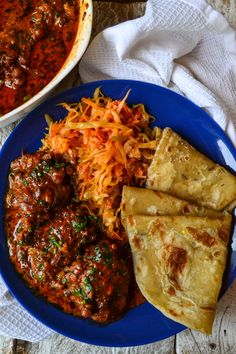 a blue plate topped with food next to a bowl of soup and pita bread