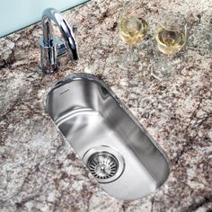 a stainless steel kitchen sink with two glasses on the counter top and one empty wine glass next to it