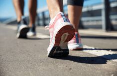 two people are walking down the street with their feet on each other's shoes