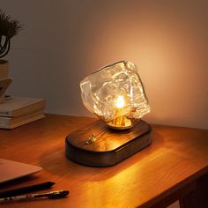 a light that is on top of a wooden table next to a laptop and pen