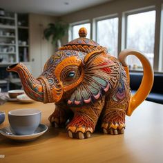 an elephant figurine sitting on top of a wooden table next to a cup