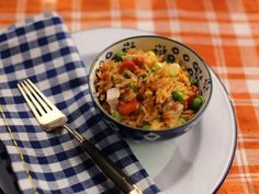 a white plate topped with rice and veggies next to a blue checkered napkin