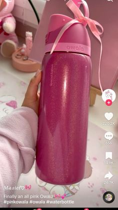 a person holding a pink water bottle with a bow on it's neck and the lid