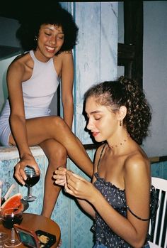 two women sitting at a table with wine glasses