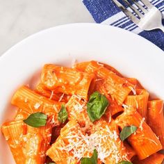 a white plate topped with pasta covered in sauce and parmesan cheese next to a fork